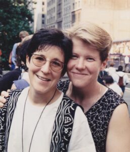 Rona and another woman smiling at a Pride march.